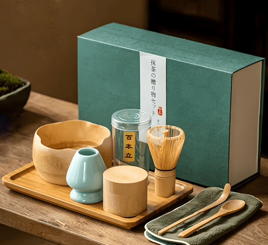 A bamboo matcha gift set displayed on a table, including a bowl, storage container, whisk, scoop, spoon, towel, stand, and tray, packaged in an elegant box.