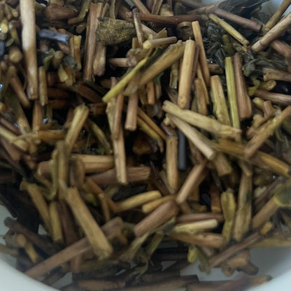 Close-up of dried herbal tea stems and leaves inside a white ceramic bowl.
