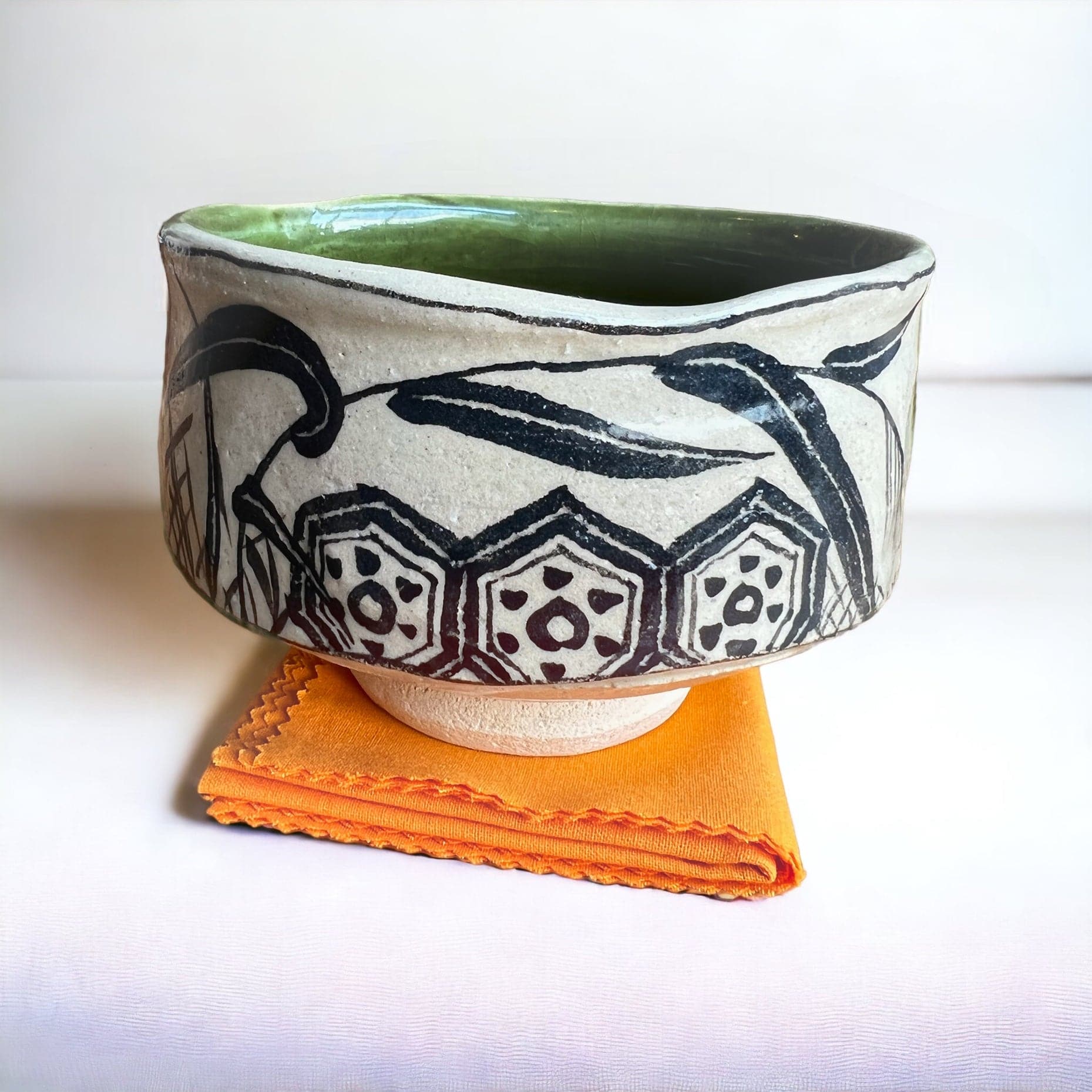 Oribe matcha bowl close up on orange tea towel.